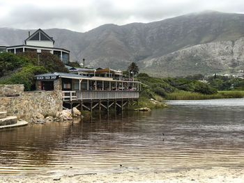 Built structure by river against mountains