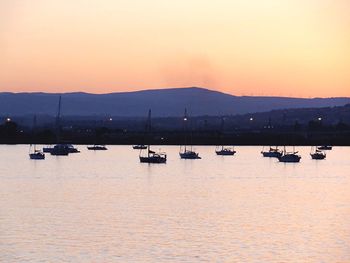 Scenic view of boats in sea at sunset