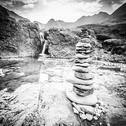 Stack of rocks by mountain against sky