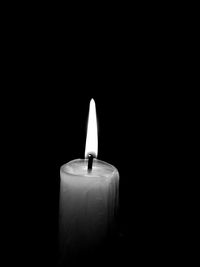 Close-up of illuminated candle over black background