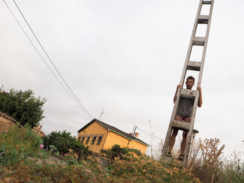 Low angle view of man standing on electricity pole