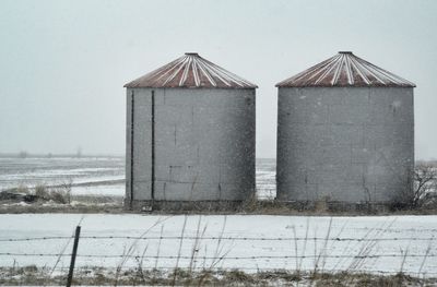 Built structure on snow covered field against sky