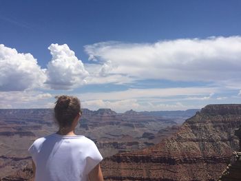 Rear view of man standing on rock against sky