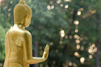 Golden buddha statue against trees