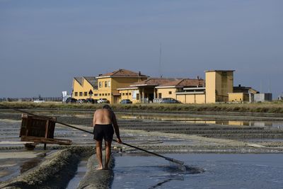 Rear view of man standing by building against clear sky