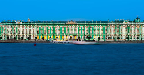 View of building by sea against blue sky