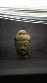 Close-up of buddha statue against window