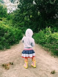 Rear view of girl standing against trees