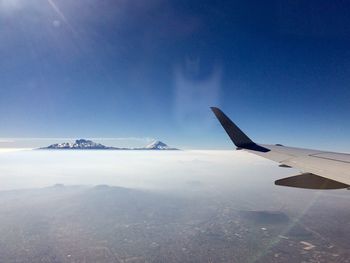 Airplane flying over snowcapped mountain against sky