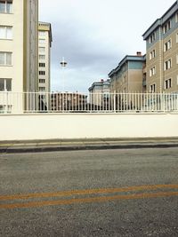 Road by buildings against sky in city