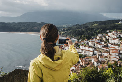 Rear view of woman photographing cityscape