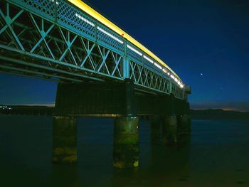 Low angle view of illuminated pier against sky at night