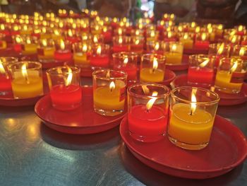 Close-up of lit tea light candles on table in temple