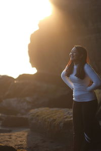 Young woman looking away while standing on rock