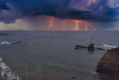 Sailboats in sea against storm clouds