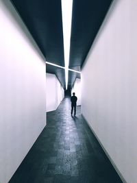 Man walking in long corridor along walls