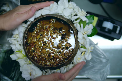 Cropped hands holding food in bowls with white flowers