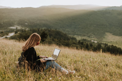 Woman with mask working on laptop in remote location