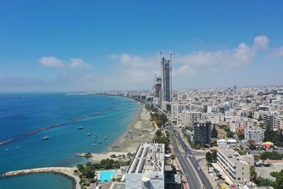 High angle view of buildings by sea against blue sky