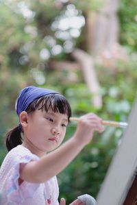 Cute asian child girl is holding paintbrush and painting on the paper. selective focus