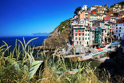 Residential buildings by sea against clear blue sky