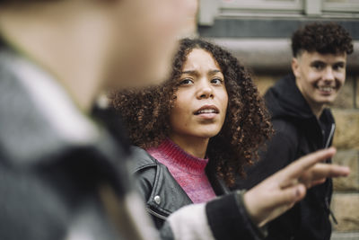 Teenage girl talking with male friend while walking at street