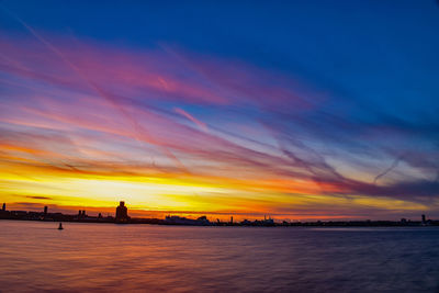 Scenic view of sea against dramatic sky during sunset