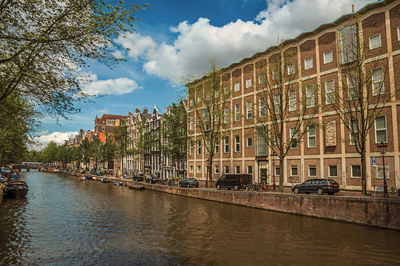 Tree-lined canal with old buildings and boats in amsterdam. the netherland capital full of canals.