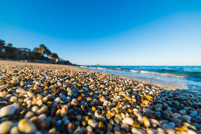 View of pebbles on beach against clear blue sky