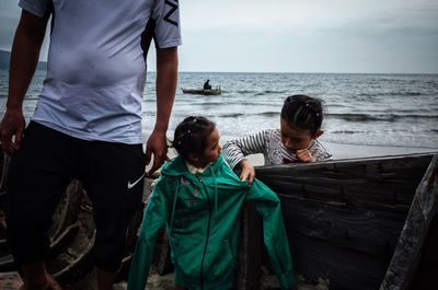 Children standing on beach against sky