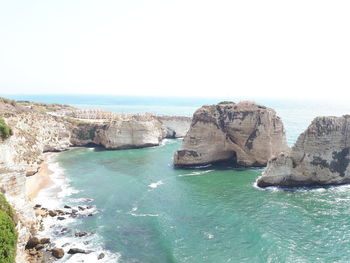 Rocks in sea against clear sky