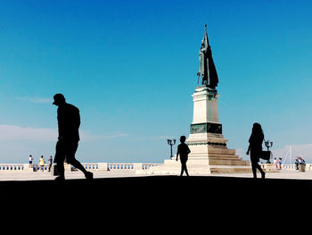Silhouette people on tower against clear blue sky