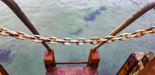 Close-up of chain on railing against sea