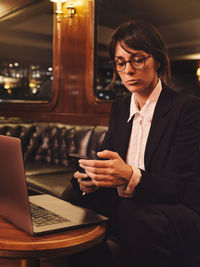 Young woman using mobile phone while sitting on table