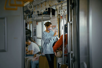 A girl takes a picture from a window using a cell phone from inside a train.