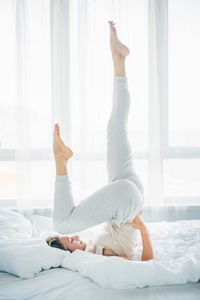 Low section of woman relaxing on bed at home