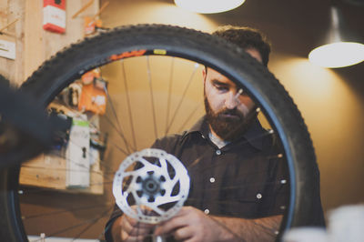 Male mechanic fixing tire at bicycle workshop