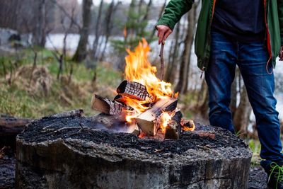 Midsection of man standing by fire in forest