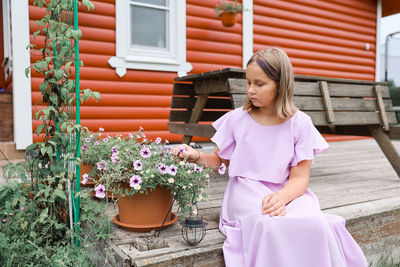 Portrait of young woman standing against window