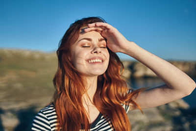 Portrait of smiling young woman against sky