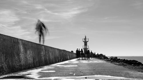 Lighthouse amidst buildings and sea against sky