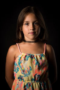 Portrait of girl standing against black background