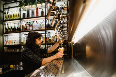 Side view of bartender filling beer glass at bar