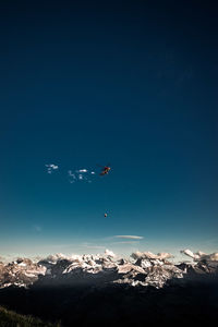 Aerial view of snowcapped mountains against blue sky