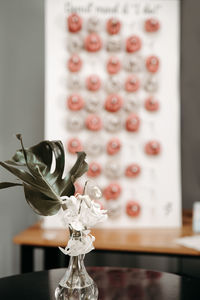 Close-up of vase with monstera plant leaf in front of donuts stand