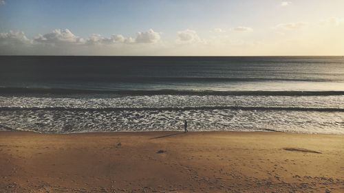 Person walking on shore at beach against sky