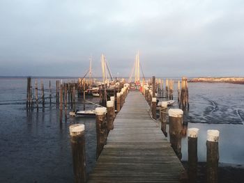 Wooden pier over sea against sky