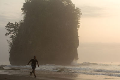 Rear view of man looking at sea against sky