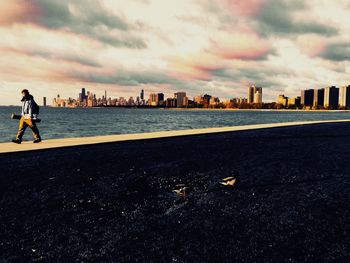 Man standing by sea against buildings in city