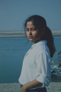 Portrait of woman standing at sea shore against sky